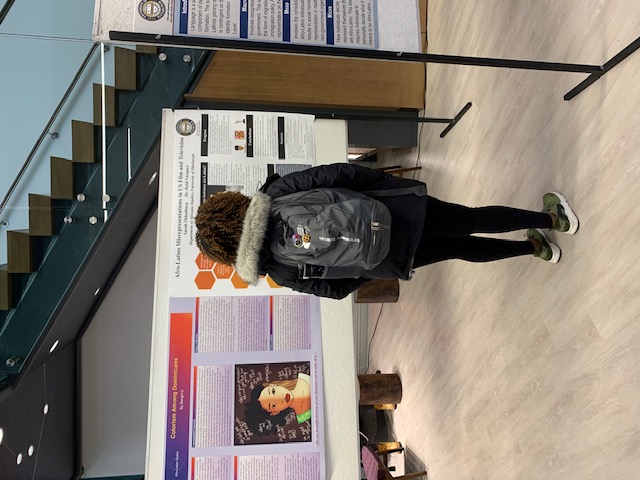 a student standing and reading a poster exhibit 