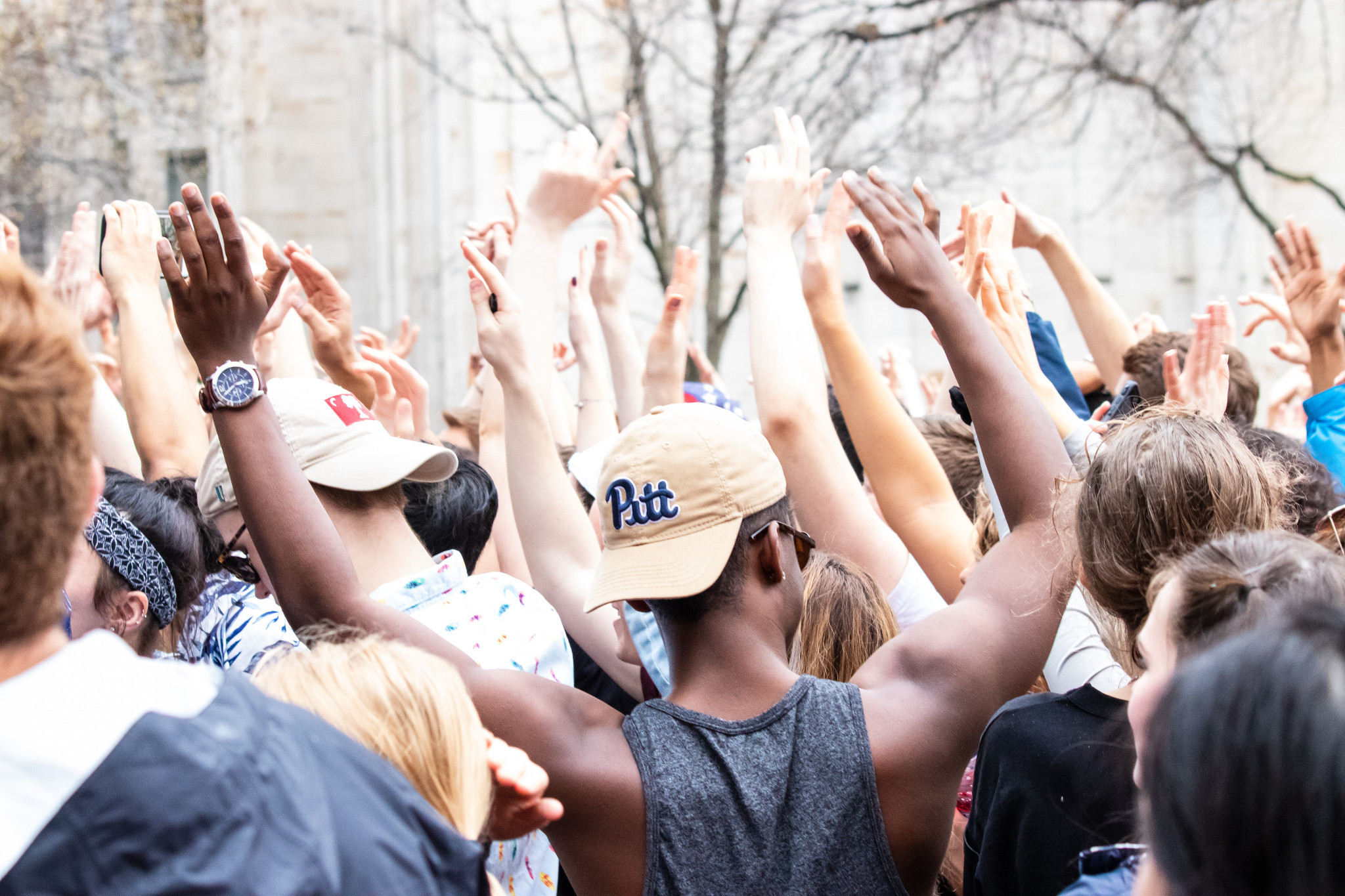 back of a crowd of students with one student wearing a Pitt hat 