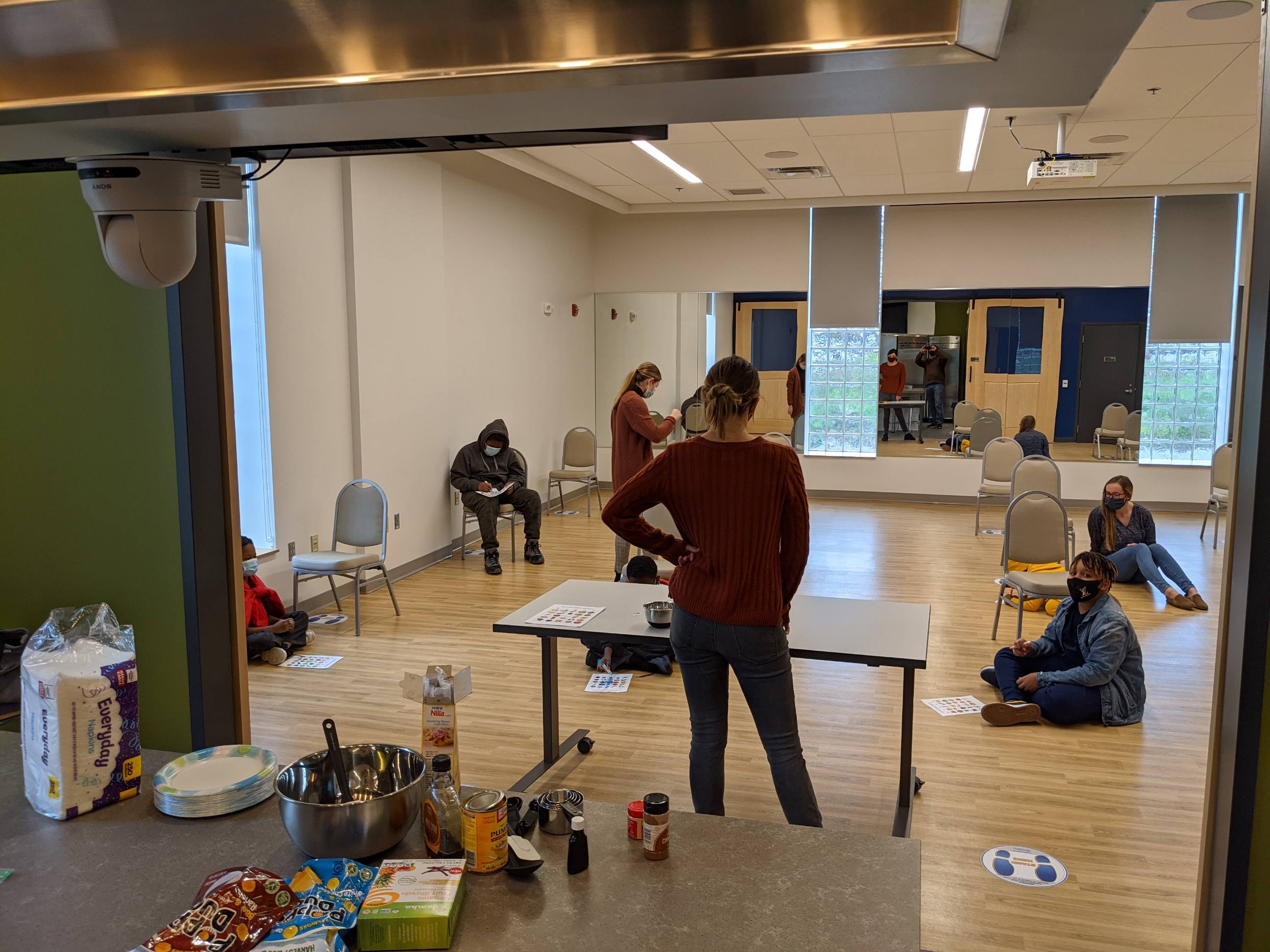 a person is getting ready to do food demo in a room, several individuals sitting around the space
