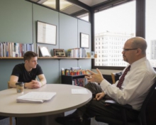 Student and professor talking at table in office