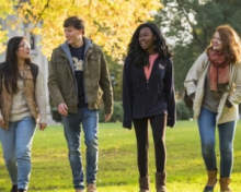 Four Pitt students walking on grass in Fall